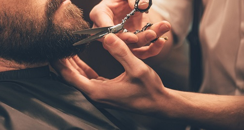 A barber trims and cuts a beard