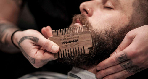 Homme qui se peigne la barbe avec un peigne à barbe Big Red Beard Combs