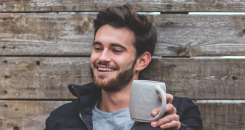 Smiling man with a short beard and a coffee