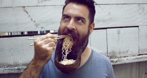 Sur cette photo, un homme mange des pâtes dans sa barbe.