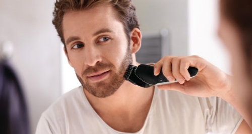 Here is a man trimming his beard with a beard trimmer