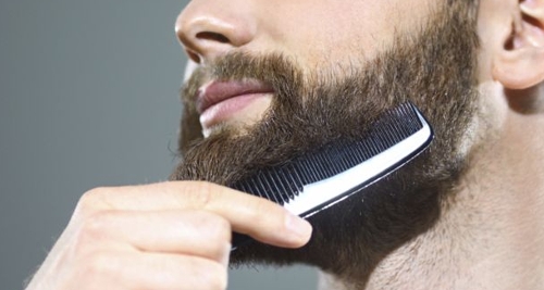 Here is a man combing his beard with a beard comb