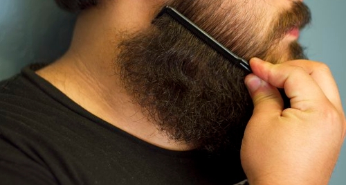 Man combing his beard with a beard comb