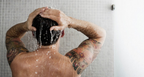 Homme tatoué sous la douche